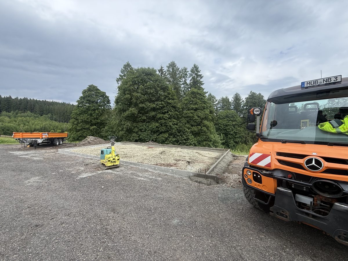 Mitarbeiter von NaturBalance neben dem Unimog auf einer Baustelle mit frisch geschotterter Fläche